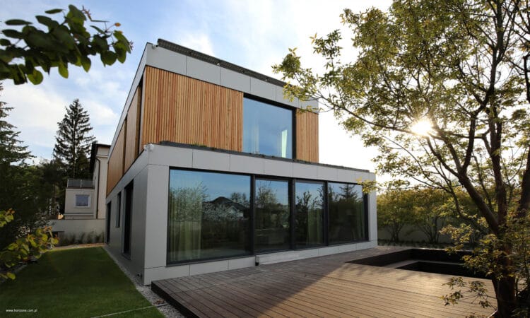 Dom na Woli Justowskiej w Krakowie, nowoczesny dom z prefabrykatów drewnianych, jasna bryła i drewniana okładzina, duże przeszklenia.